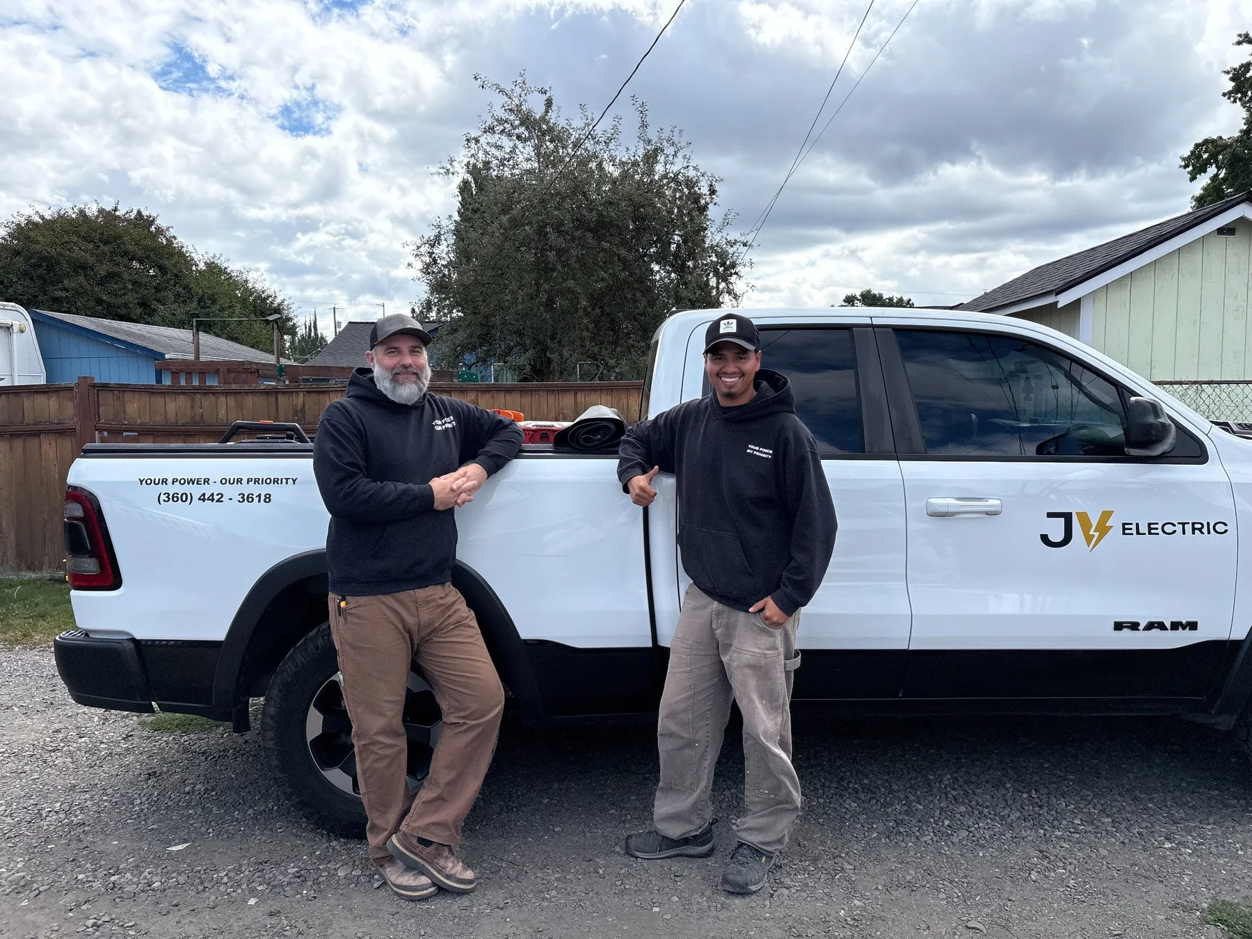 JV Electric electricians beside a branded work truck